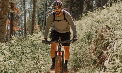 A beautiful community at the heart of all your passions man riding a bike on a trail in the woods
