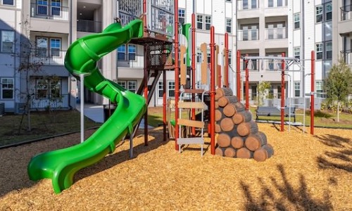 Modern playground with a green spiral slide at Solaris, highlighting family-friendly apartment rentals in Kissimmee.