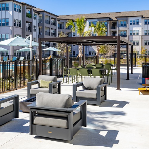 Outdoor lounge and patio area with fire pit and games at luxury apartments in Kissimmee, FL.