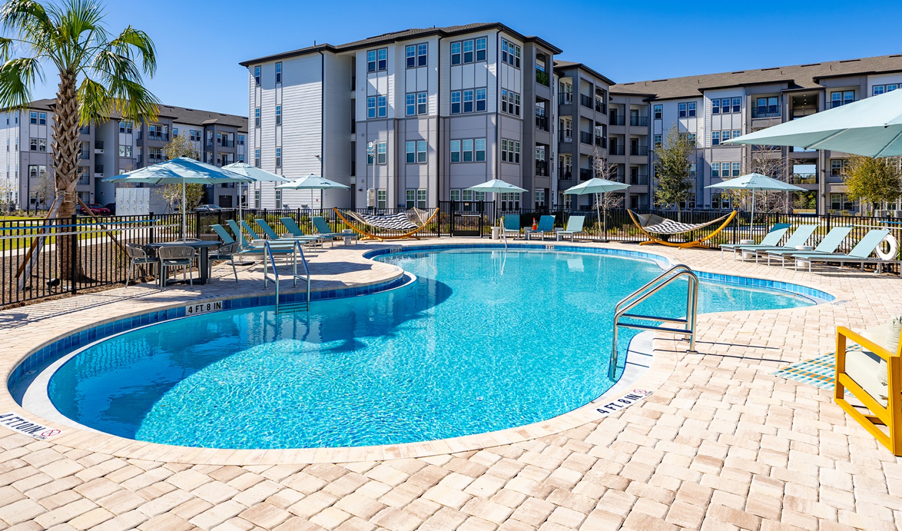 Sparkling resort-style swimming pool surrounded by lounge chairs at Solaris apartments, Kissimmee, FL.